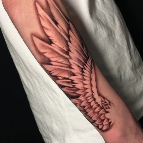Realism wing tattoo on forearm.